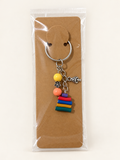 Golden Garden Book Stack Keychain on a kraft card in a clear sleeve