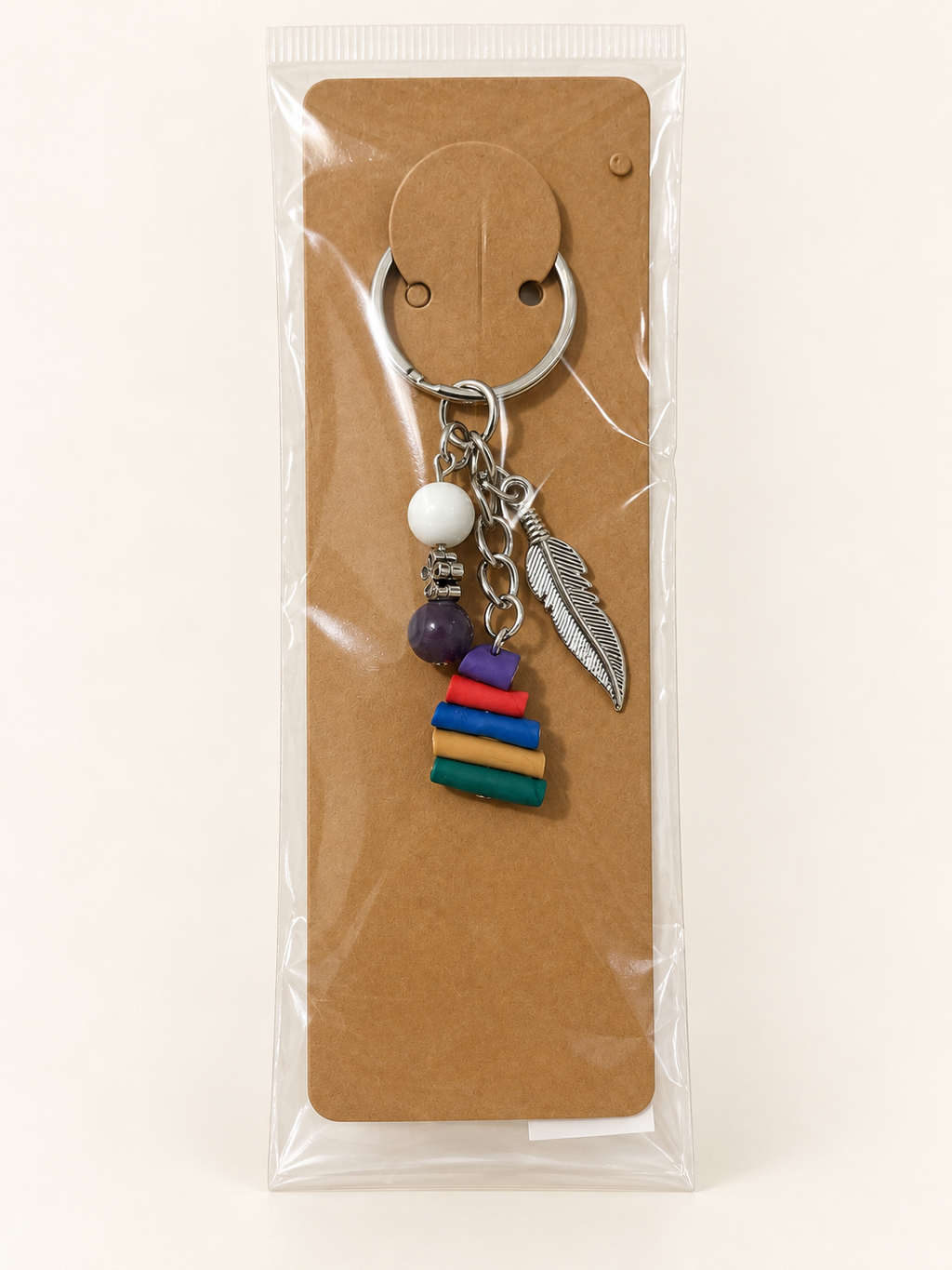 Feathered Book Stack Keychain on a kraft card in a clear sleeve