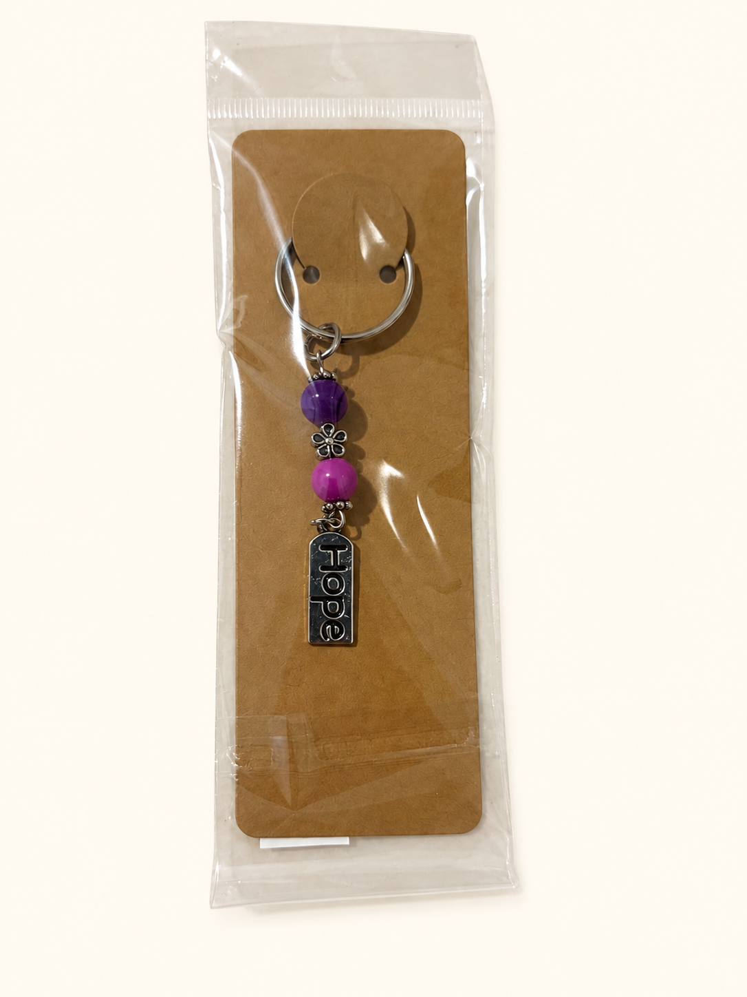 Hope Word Bead Keychain with purple and magenta beads, packaged on a kraft card in a clear sleeve