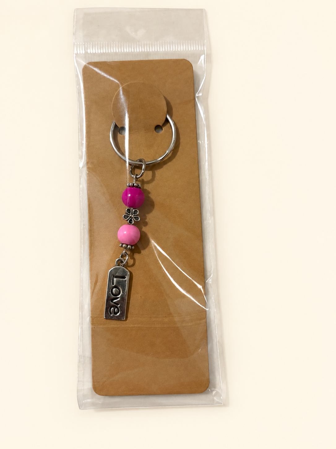 Love Word Bead Keychain with magenta and pink beads, packaged on a kraft card in a clear sleeve