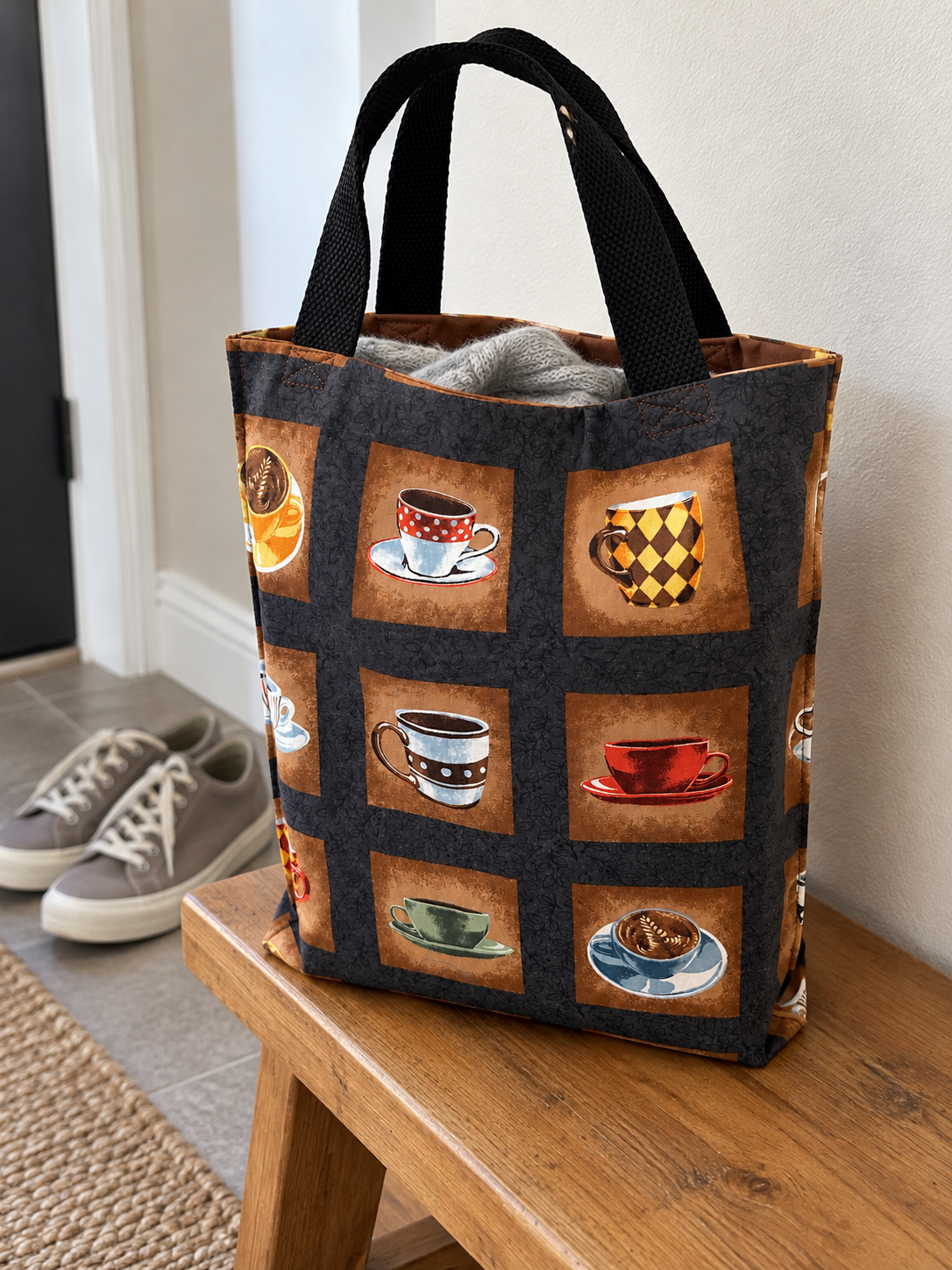 Lifestyle mockup of Coffeehouse Cups tote holding a folded sweater